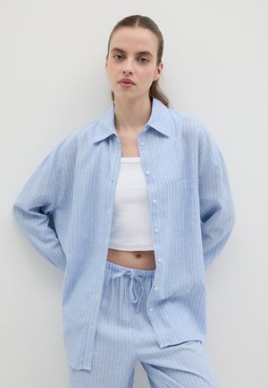 Camisa de botones a rayas azul y blanca con un bolsillo, combinada con pantalones de tiro ajustable en azul claro. Tela suave y corte relajado.