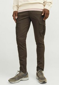 Bruine cargobroek van twill stof, met zijzakken en een slim fit ontwerp. Gecombineerd met grijze sneakers.