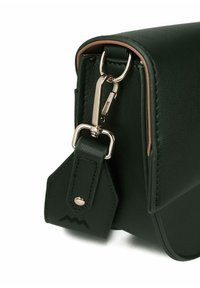 Zelená kožená crossbody taška se zlatými detaily, s uzavíráním na západku a odnímatelným štítkem s logem. Hladký povrch, kompaktní tvar.