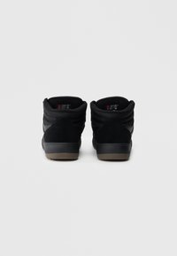 Crne visokotopke s teksturiranim antilop završetkom, podstavljenim ovratnikom i gumeni đonom. Imaju logotip oznake na peti i jeziku.