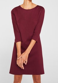 Burgunderfarbenes Kleid mit Dreiviertelärmeln, rundem Ausschnitt und gerader Passform. Hergestellt aus einem strukturierten Stoff mit glatter Oberfläche.