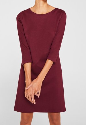 Vestido burdeos con mangas de tres cuartos, escote redondo y corte recto. Hecho de una tela texturizada con un acabado suave.
