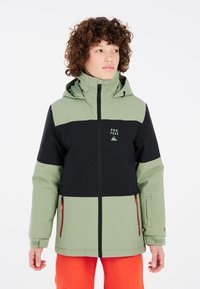 Veste de ski imperméable verte et noire avec zip à l'avant, capuche, poches zippées et logo. Présente des blocs de couleurs contrastantes et une texture douce.