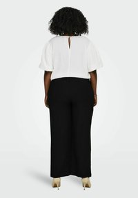 Baltas tekstūruotas viršus su pūstomis rankovėmis ir atviru nugara, derinamas su aukštu liemeniu juodais plačiais kelnais ir nuogais aukštakulniais.