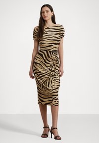 Beige off-the-shoulder mekko, jossa on mustia tiikeriraitoja, drapeerattu malli, polven pituinen, yhdistetty mustien hihnakenkien ja renkaankorvisten kanssa.