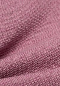 Tissu tricoté rose présentant un tissage texturé, affichant une surface douce et légèrement duveteuse avec un dégradé de tons colorés.