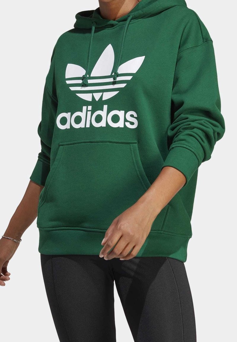 Green hoodie made of soft fabric featuring a large white Adidas trefoil logo and drawstrings, with a front pocket and ribbed cuffs.