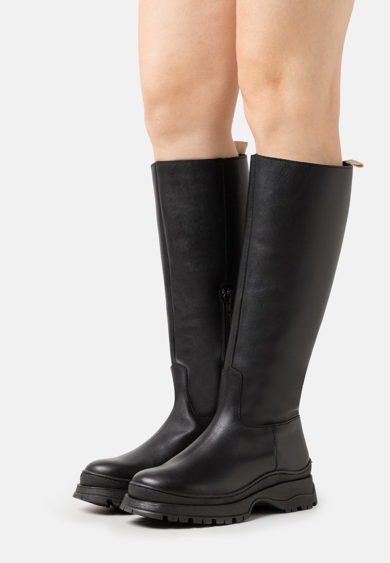 Bottes noires hautes jusqu'aux genoux en cuir lisse, dotées d'une fermeture éclair latérale, d'une semelle en caoutchouc épaisse et d'un bout rond. Conçues avec un profil minimaliste.