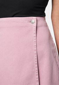 Rosa denimkjol med rak skärning, som har en sidoknappslåsning och synliga sömdetaljer. Tyget har en lätt textur.