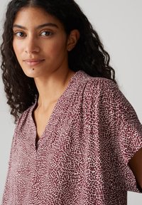 Haut bourgogne avec un motif texturé blanc, doté d'un col en V et de manches courtes, fabriqué en tissu léger.