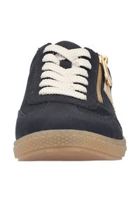 Black sneaker with white laces, beige accents, and a side zipper. Features a textured rubber sole and smooth upper material.