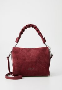 Maroon suede handbag with a braided top handle, detachable shoulder strap, and silver hardware. Smooth texture with logo detailing.