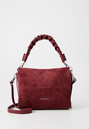 Bordo zamšas rokassoma ar pītām augšējām rokturiem, noņemamu plecu siksnu un sudraba aparatūru. Gluda tekstūra ar logo detaļām.