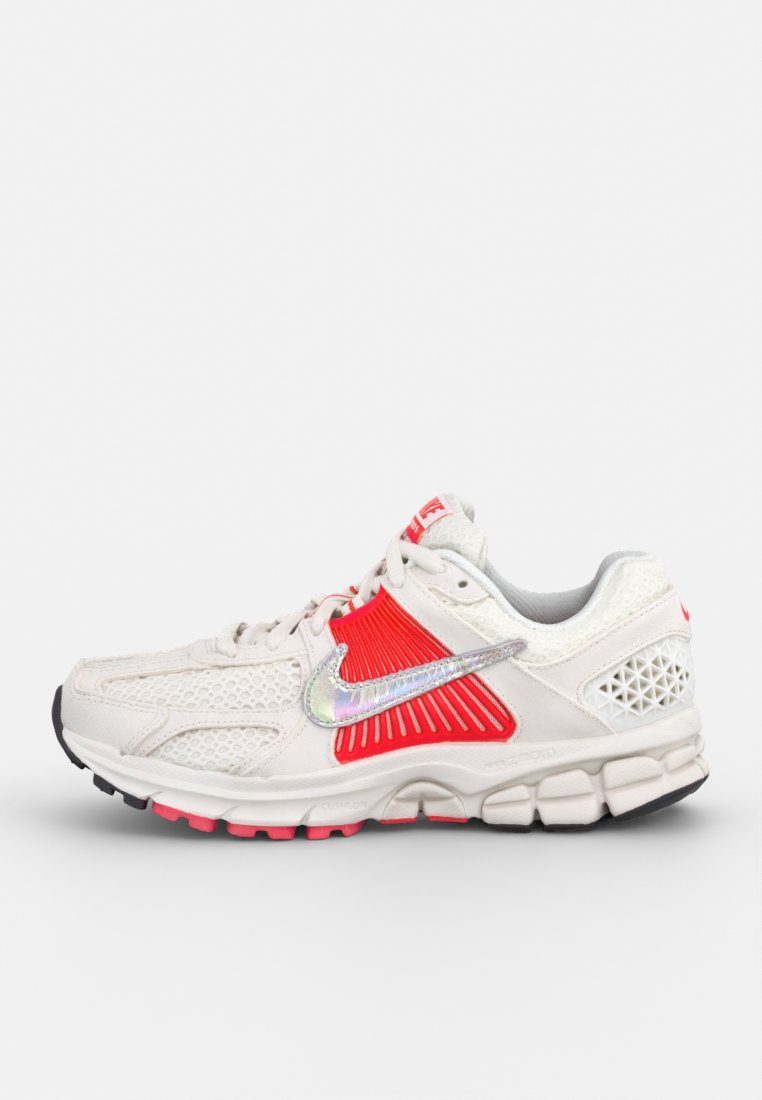 Baskets de sport blanches avec des accents rouges et argentés, des panneaux en mesh pour la respirabilité, une semelle rembourrée et un design texturé pour l'adhérence.