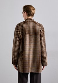 Bruin en zwart houndstooth-patroon overshirt met een relaxte pasvorm, voorzien van lange mouwen, een rugplooi en knoopmanchetten.