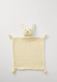 Mehka rumena muslin odeja s zajčkom oblikovano glavo, ki ima izšite obrazne detajle in štiri zavezane vogale za teksturo.