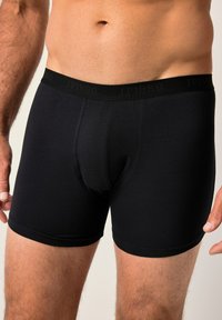 Boxers negros ajustados hechos de tejido elástico, con un acabado suave y una cinturilla elástica con un branding sutil. Diseñados para un ajuste ceñido.