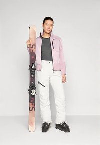 Equipamento de esqui com uma jaqueta rosa claro, camisa cinza escuro, calças brancas, botas de esqui pretas e uma prancha de snowboard com detalhes rosa e pretos.