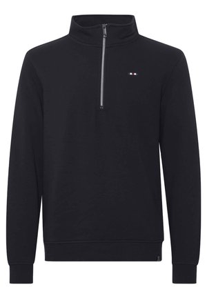 Melnā ceturtdaļa zip svītrai ar mīkstu audumu. Iespējas iekļauj augstu apkakli, garas piedurknes un mazu logotipu ar sarkaniem, baltajiem un zilajiem akcentiem.