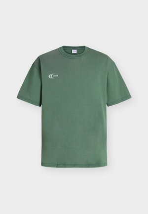 Πράσινο T-shirt με κοντά μανίκια και στρογγυλή λαιμόκοψη με μικρό λευκό λογότυπο ARKK στο αριστερό στήθος, εμφανιζόμενο σε απλό ανοιχτό φόντο.