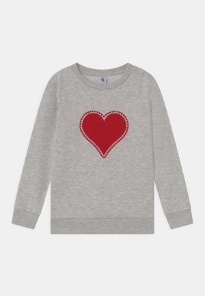 Lys grå langærmet skjorte med et stort rødt hjerte omgivet af små hjerter trykt i centrum.