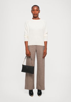 Cream sweater with ribbed cuffs, checkered wide-leg trousers in brown and beige, black handbag with chain strap, and pointed black heels.