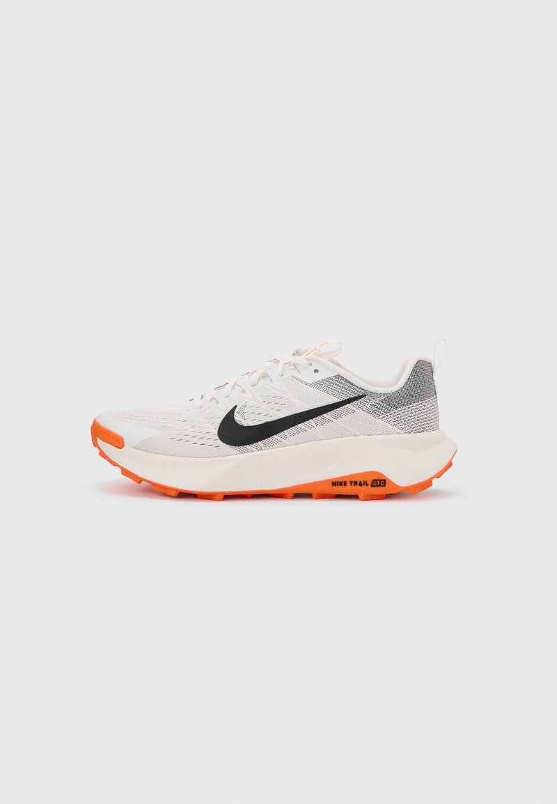 Άσπρο και γκρι παπούτσι για τρέξιμο σε μονοπάτια Nike με μαύρο σήμα και φωτεινή πορτοκαλί σόλα, απεικονισμένο σε πλάγια όψη σε απλό φόντο.