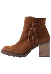 Brązowe zamszowe botki za kostkę z szerokim obcasem, ozdobione frędzlami i okrągłym noskiem. Teksturowana gumowa podeszwa oraz kontrastowe przeszycia.