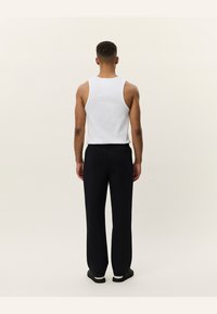 Hvid ærmeløs tanktop parret med sorte tapered bukser. Outfittet har et enkelt, afslappet design og komfortabelt stof.