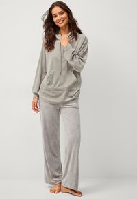 Šedý velurový loungewear set obsahující mikinu s kapucí a předním kapsou a volné široké kalhoty se hladkým povrchem.