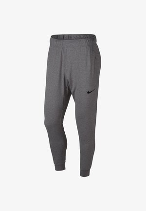 Pantalones deportivos gris ajustados con cintura y puños elásticos, que cuentan con un pequeño logo de Nike en negro en la parte superior del muslo izquierdo.