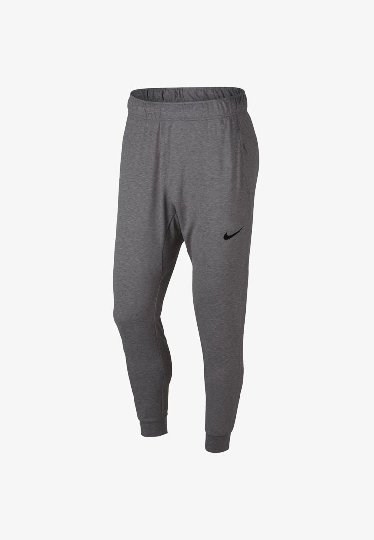 Pantalons de sport gris fuselés avec une taille élastique et des poignets, présentant un petit logo Nike en forme de virgule noir sur la cuisse supérieure gauche.
