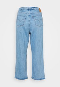 Vaqueros de denim azul claro con un corte relajado, piernas anchas y recortadas, y bolsillos traseros con detalles de costura. Etiqueta de marca de cuero marrón en la cinturilla.