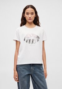 Hvit bomulls-T-skjorte med et grafisk design av lepper i nyanser av rosa og grått. Korte ermer, rund hals og avslappet passform.