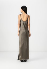 Rochie maxi din satin argintie, cu un decolteu adânc la spate, bretele subțiri, fante laterale și o textură netedă. Marginea ajunge până la glezne.