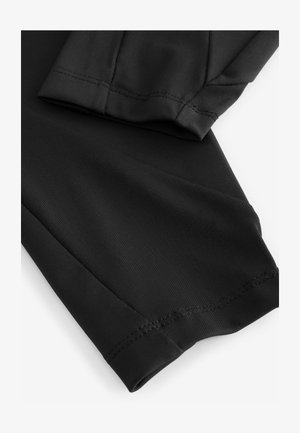 Must mustra, tumeda sportlik kangas, mis tõmbab tähelepanu oma siledale tekstuurile ja nähtavale õmblusele, struktuurne disain on stiilne ja minimalismi hõlmav.