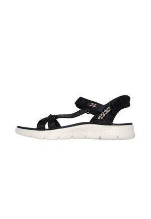 Sandalia negra con tiras de tela, diseño anudado y correa para el talón ajustable; suela blanca acolchada con superficie texturizada y detalles del logo.