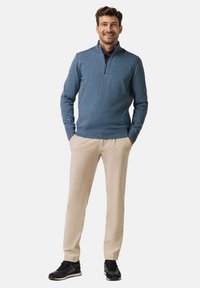 Blue pullover sweater with a zip collar, paired with beige pants and black sneakers. The fabric appears soft and textured.