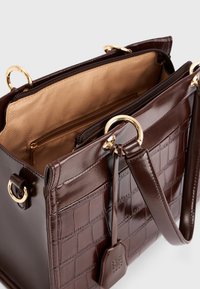 Braune Handtasche aus Leder mit Krokodilprägung, goldenen Hardware-Accents und einem gefütterten Innenraum. Verfügt über ein Reißverschlussfach und einen abnehmbaren Anhänger.