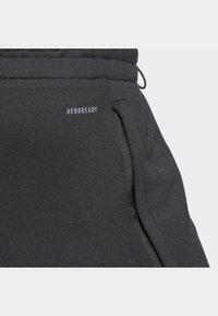 Pantalones atléticos negros con tejido texturizado, que cuentan con un bolsillo lateral y la marca AEROREADY. Cintura elástica para un ajuste ajustable.