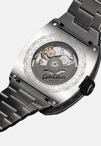 Automatic watch with a stainless steel case, exposed movement, engraved brand name, crown, and a textured bracelet. Water resistant to 50m.