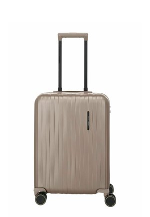 Maleta rígida beige con estrías verticales, cuatro ruedas giratorias y un asa telescópica negra y beige extendida.