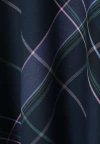 Tissu bleu marine avec un motif à carreaux en lignes roses, vertes et bleues. Surface texturée avec un tissage visible et une brillance.
