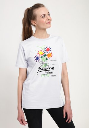 Weißes Baumwoll-T-Shirt mit farbenfrohem Blumen-Design, Handillustration und Schriftzug, getragen zu schwarzen Jeans. Kurze Ärmel, Rundhalsausschnitt.