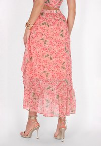 Roze bloemen maxi-rok met een gerimpelde zoom, gemaakt van een semi-doorzichtig, lichtgewicht materiaal en een natuurlijke taille, gecombineerd met strappy hakken.