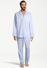 Vaaleansininen pyjama-asusetti, joka on valmistettu pehmeästä kankaasta. Pitkähihainen napitettava paita, jossa on rintatasku, samanlaiset kapenevat housut ja kontrastiväriset pipings yksityiskohdat.