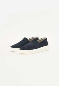 Scarpe slip-on in suede blu navy con colletto imbottito, caratterizzate da una suola in gomma bianca e dettagli di cucitura discreti sulla parte superiore.