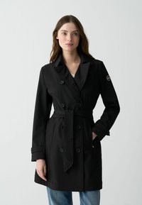 Černý trench coat s dvojřadým zapínáním, opaskem v pase a klasickým límcem. Vyroben z hladkého materiálu s manžetami na knoflíky.