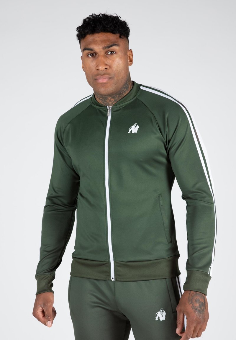 Grüne sportliche Zip-Jacke mit weißen Streifen an den Schultern, ausgestattet mit einem Frontreißverschluss, gerippten Bündchen und einem Logo auf der Brust.