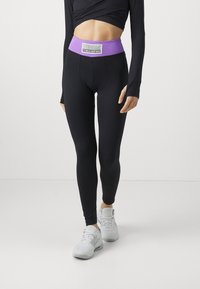 Leggings pretos com uma cintura alta roxa, apresentando o logótipo 'NEBBIA FITNESS INSPIRED', textura suave e design ajustado ao corpo.